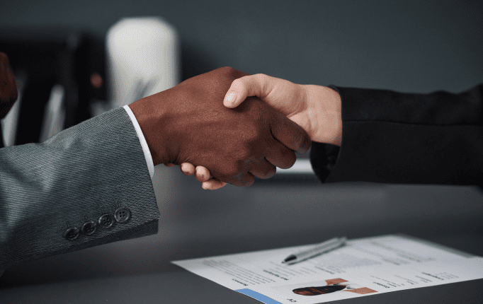 Two people shaking hands over a table